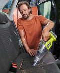Man using Compact 18V Lithium Ion Handheld Vacuum With Beast Mode Suction Power And Double Mesh Filtration Setup in car.