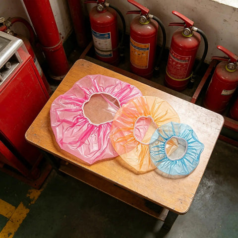 Heavy Duty Fire Alarm Dust Caps For Paint Day The 96 Piece Universal Flexible Heat Detector And Sprinkler Guard in pink, orange, and blue on a wooden table.
