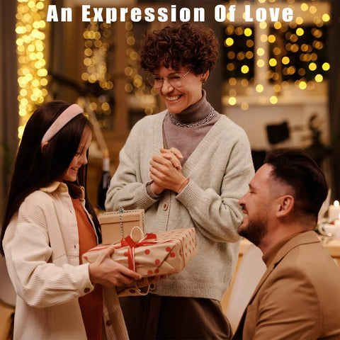 An Expression Of Love text above three people exchanging wrapped gifts at a warm indoor celebration