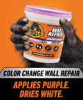 Color Changing Wall Repair Compound 16 Ounce Tub Goes Purple When Applied And Dries White held by gorilla hand