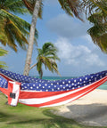 XL Beefy Double Camping Hammock With Tree Straps For Indoor And Outdoor Use Portable Gear That Holds Up To 500 Lbs Extra Large 125 In By 79 In Perfect For Two People And Weekend Chill Sessions hanging between palm trees on a beach, American flag design.