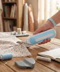 Hassle Free Cordless Electric Fabric Scissors With Ergonomic Comfort Grip cutting floral fabric on a wooden table.