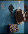 Six Pack Rock Solid Cast Iron Wall Hooks With Rustic Indian Leaf Design Heavy Duty Matte Black Finish holding a hat and embellished bag.
