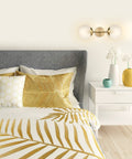 Celestia 2-Light Wall Sconce In Matte Brass With Frosted Glass Shades above a modern bedroom nightstand