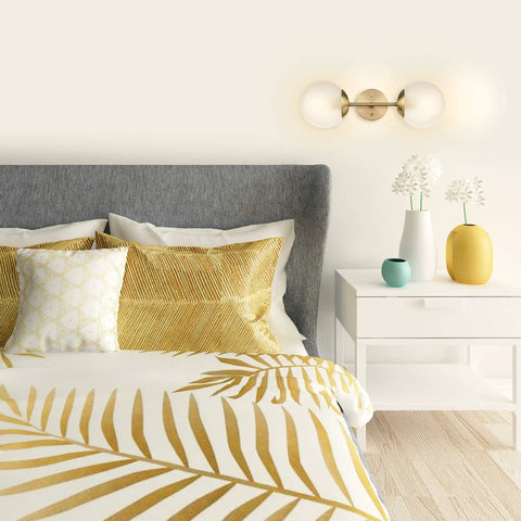 Celestia 2-Light Wall Sconce In Matte Brass With Frosted Glass Shades above a modern bedroom nightstand