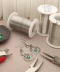 304 Stainless Steel Wire Pro Grade 16 Gauge Round, Tarnish Resistant 8 Yard Spool with tools and jewelry on a table