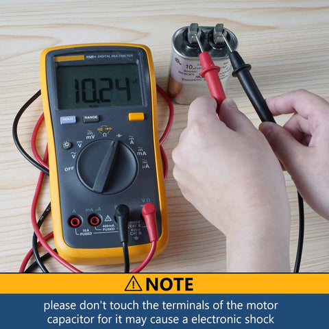 Person testing 10 MFD 370 440 VAC Round Motor Run Capacitor with multimeter, focusing on safety note about electronic shock.