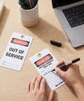 No Sweat Bulk 50 Pack Danger Out Of Service Tags For Industrial Facilities With Double Sided Bold Print and Marker Pen on a desk.