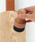 Hand using the Straight Up Amazing Wooden Cutting Board Oil Brush And Built Tough Wood Wax Applicator Sponge on a light wood cutting board.