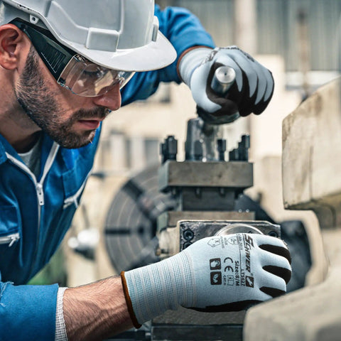 Man in blue uniform wearing Six Pairs Heavy Duty Work Gloves With Sandy Nitrile Coating Extreme Fiber Abrasion Resistance Level 6 Certified A2 Cut Protection Grippy For Construction Men and Women working with machinery.