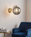 Mid‑Century Modern Globe Glass Wall Sconce with Wine Red Hand‑Blown Glass, ribbed glass shade on brass arm, soft glow.
