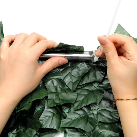 Hands installing Faux Ivy Privacy Fence Panel For Outdoor Spaces Heavy Duty Hedge Screen With Realistic Leaves Low Maintenance
