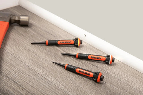 Three-piece set of 5 Inch Gripped Punch Set With Full Metal Core And Comfort Grip on a wooden surface.