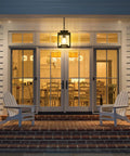 Modern Farmhouse Outdoor Pendant Light for Porch hanging on veranda with glass cylinder, casting warm light.