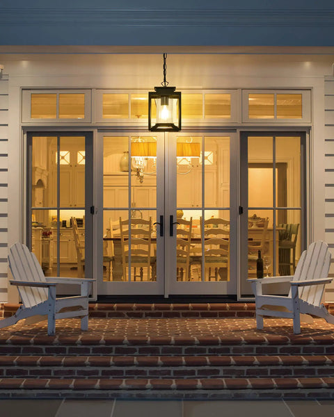 Modern Farmhouse Outdoor Pendant Light for Porch hanging on veranda with glass cylinder, casting warm light.