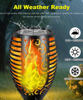 Close-up of 4 Pack 96 LED Solar Tiki Torches With Flickering Flame showing waterproof feature in rainy garden setting.