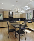 Modern kitchen with geometric pendant light, beige cabinets, black countertops, and dining table with black chairs.