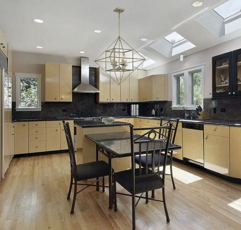 Modern kitchen with geometric pendant light, beige cabinets, black countertops, and dining table with black chairs.