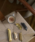 Assorted metallic drawer pulls on woven chair with coffee mug, showing different finishes and styles.