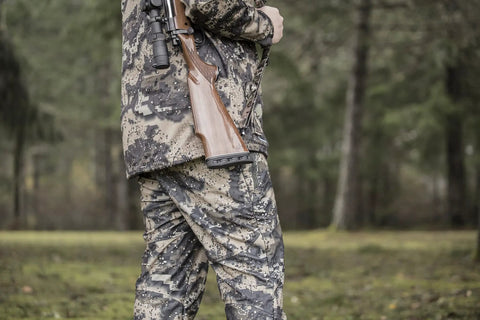Hunter carrying rifle with AirTech Precision-Fit Recoil Pad for Christensen Arms, Marlin, and Remington rifles in forest.