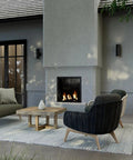 Outdoor patio scene with 5 Inch Cylinder Outdoor LED Wall Sconce with 2 Lights Up and Down mounted beside a modern fireplace.