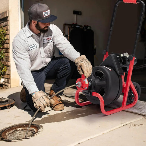Heavy Duty Workhorse Electric Drain Auger Machine With Automatic Forward And Reverse Footswitch Control Plug And Play Badass Performance For Pro Plumbers One Hundred Feet By Three Eighths Inch Steel Cable Six Sharp Cutters Clears Gnarly Sewer Clogs Smooth in use with operator handling.
