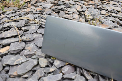 Close-up of Pro-Grade Magnesium Concrete Float 3-1/8 x 16 In with beveled ends, shown on rocky ground surface.