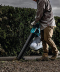 Person using 3-In-1 Cordless Leaf Blower Vacuum Mulcher, 18V LXT Brushless Tool in vacuum mode on gravel path