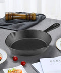 Six Inch Cast Iron Skillet With Drip Spouts For Even Heat on a table with a wooden pepper mill and plates with food