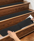 Hands applying Heavy Duty Three Pack 6x24 Inch Non Slip Stair Treads with Black High Traction Adhesive Tape for steps