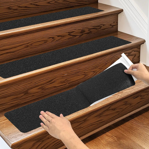 Hands applying Heavy Duty Three Pack 6x24 Inch Non Slip Stair Treads with Black High Traction Adhesive Tape for steps