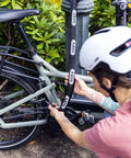 Person securing a bike to a lamppost with Frame Lock Insert Chain Adaptor Chain 2.0 6KS for secondary bike security, 100 cm long, black.