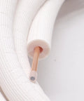 Close-up of 1/4-inch insulated copper refrigerant line with white foam insulation