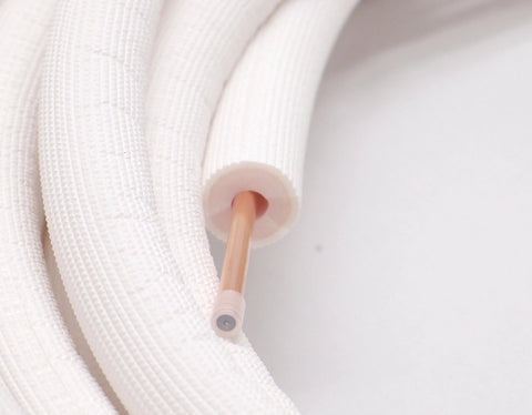 Close-up of 1/4-inch insulated copper refrigerant line with white foam insulation