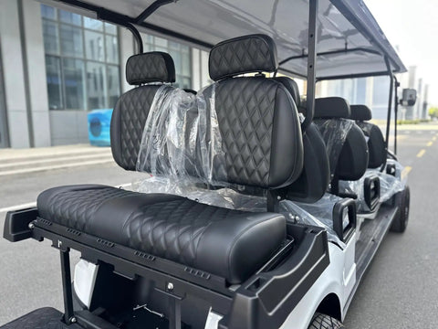 White Eight Passenger Electric Golf Cart Rolled Up Tight With Beefy Dual Arm Suspensions Silky Smooth Five Kilowatt Motor Plus Touchscreen Audio And Deep Reclining Lounge Seats featuring black diamond-stitched lounge seats.