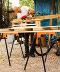 A person using Heavy Duty Foldable Saw Horses 2 Pack Supporting 1322 Lbs With Toughened Steel Rig for carpentry.