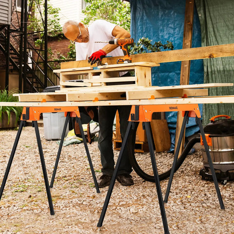 A person using Heavy Duty Foldable Saw Horses 2 Pack Supporting 1322 Lbs With Toughened Steel Rig for carpentry.