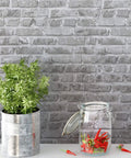 Grey Faux Brick Peel And Stick Wallpaper Roll 17.7 By 472 Inches Self Adhesive Vinyl Film for Easy DIY, plant pot and glass jar displayed.