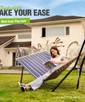 Beefy Heavy Duty Steel Hammock Stand For 9 To 14 Foot Hammocks With 550 Lb Capacity, Portable Frame, Carry Bag Included, Dual Bar Design For Stability, Indoor Outdoor Use, Black in a backyard with woman reading.