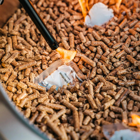Close-up of Bonfire Pellet Adapter For Outdoor Fire Pits Dual Fuel Upgrade in use with wood pellets burning in stainless steel extension.
