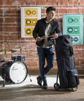 Heavy Duty Rolling Drum Cart With Removable Nylon Gear Bag And Tough Steel Frame, held by a drummer in a studio setting.