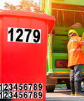 Bold White Vinyl House Numbers Two Sets Of 6 Inch Pre Spaced Address Stickers on red bin beside garbage truck