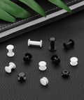 Top Shelf Black Plastic Chicago Screws 50 Piece Set Binding Posts M5x3mm Press On Buckles on black leather background.