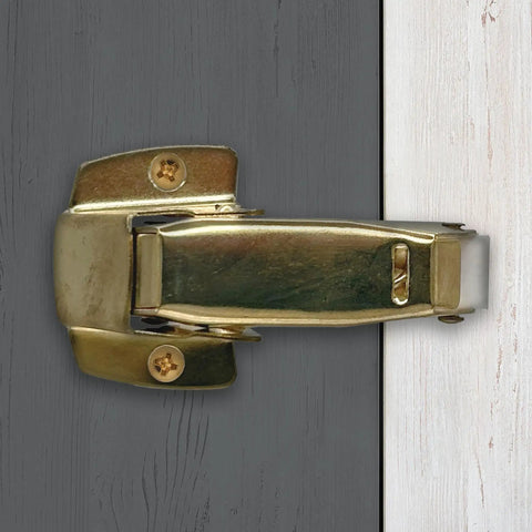 Built Tough Spring Loaded Screen Door Catch Slick Brass Finish Iron Frame close-up, mounted for secure entryway locking.