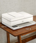 Side view of Envy 6555e Wireless All-In-One Color Inkjet Printer With Duplex Printing on a wooden table, dimensions visible.
