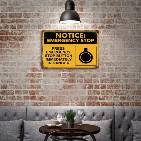 Emergency Stop Button Safety Sign Vintage Tin Wall Decor 8x12 Inch Yellow And Black Industrial Plaque on brick wall in cozy setting.