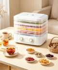 Big Time 6 Tray Food Dehydrator For Home With Clear Racks And Digital Temperature Timer Controls To Knock Out Homemade Jerky Dried Fruit Veggies And Dog Treats Quick As Can Be on a tabletop with various dried snacks.