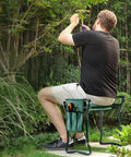 Person sitting on Versatile Garden Kneeler And Seat Foldable Bench With Tool Pouch in garden setting, focusing on DIY yard projects.