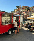 13 Foot Red Fiberglass Food Truck Fully Loaded Mobile Kitchen With Commercial Grade Prep Tables Built In Cooking Gear Street Ready Catering Rig For Busy Weekend Markets and Turnkey Business Ventures serving customers at a waterfront.