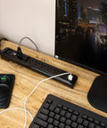 Dope UltraPro 7 Outlet Surge Protector With USB Ports on desk, 4 foot cord, black, powering monitor and charging phone.